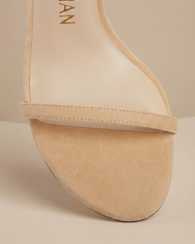 Beige suede open-toe sandal with single strap and minimalist design on neutral background