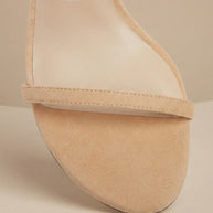 Beige suede open-toe sandal with single strap and minimalist design on neutral background