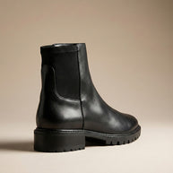 Black leather ankle boot with chunky sole and elastic side panel on neutral background