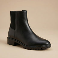 Black leather ankle boot with chunky sole on neutral background