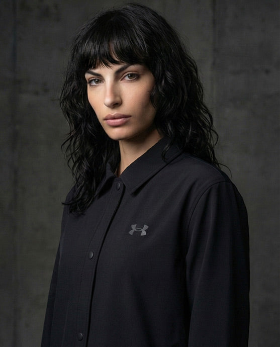 Woman wearing black athletic jacket with logo, button-up front, and pointed collar