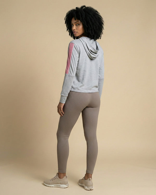 Woman in gray hoodie with pink sleeve stripes and taupe ribbed leggings, beige sneakers