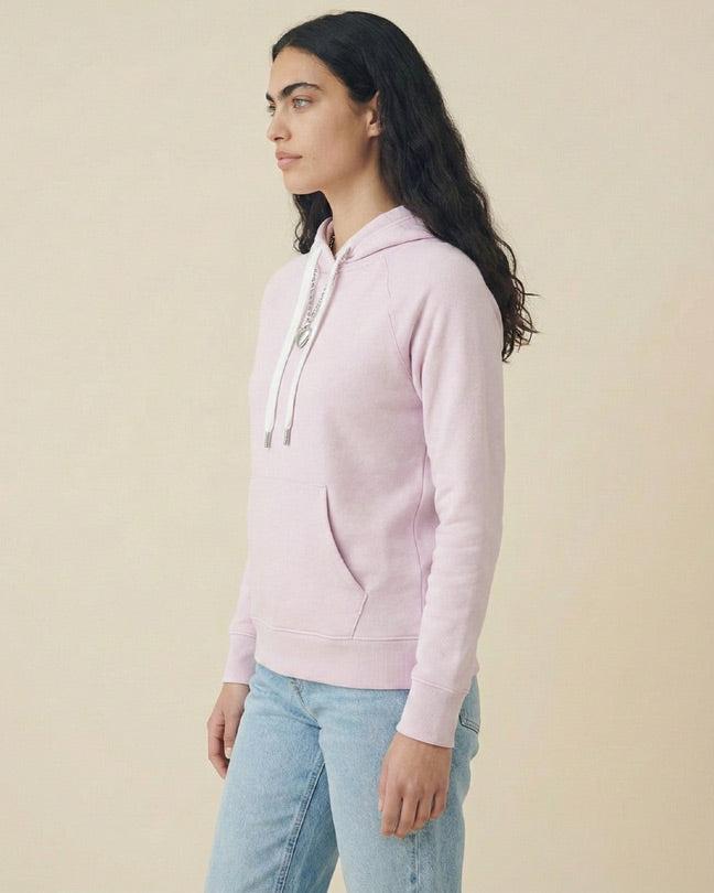 Woman wearing light pink hoodie and blue jeans in studio, casual fashion