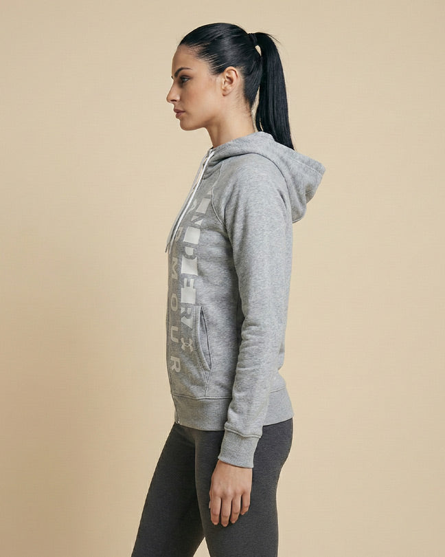 Woman in profile wearing a grey hooded sweatshirt and leggings, studio background