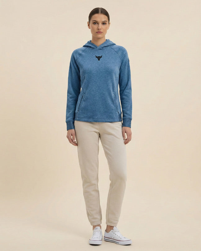 Woman wearing blue hooded sweatshirt with bull logo and beige joggers, casual outfit