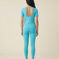 Woman wearing light blue athletic shirt with open back and matching leggings, rear view