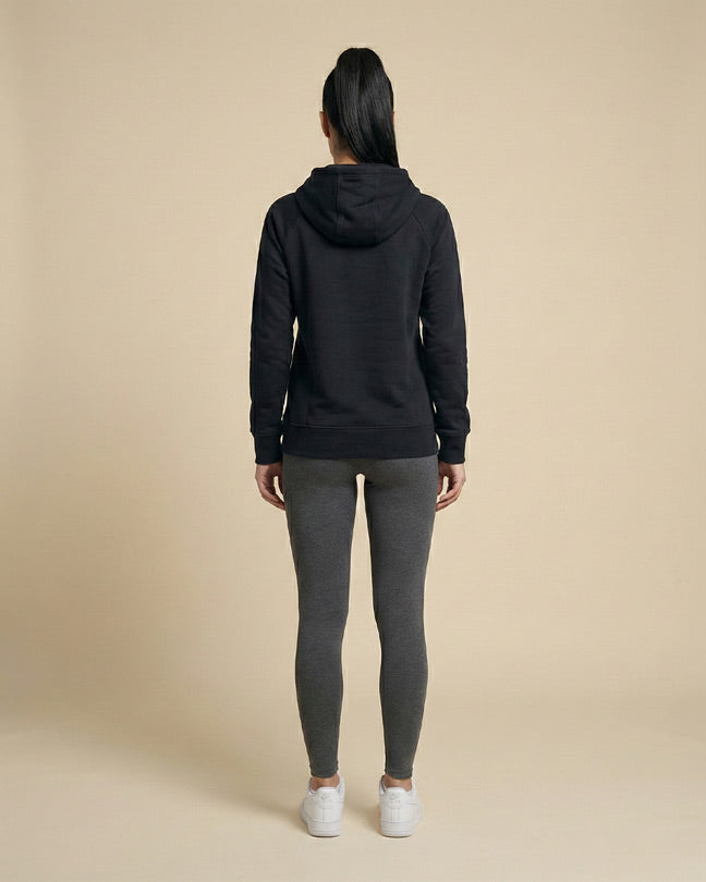 Woman wearing black hoodie, gray leggings, and white sneakers viewed from the back