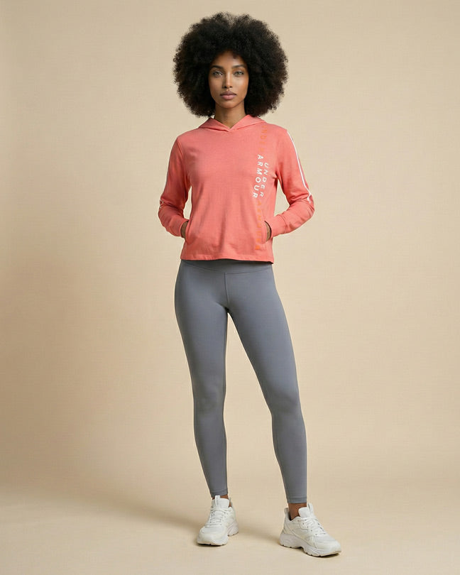 Woman wearing a pink hoodie with text and gray leggings, standing on a neutral background