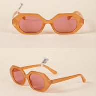 Geometric orange sunglasses with pink lenses on a neutral background