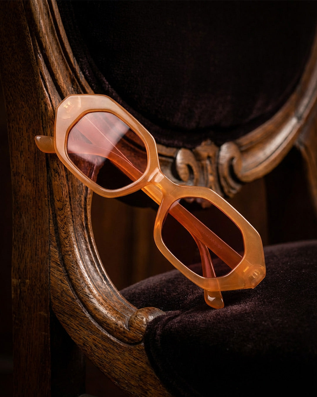 Geometric orange sunglasses with tinted lenses on a vintage wooden chair