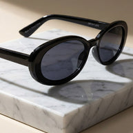 Black oval sunglasses with dark lenses on a marble slab, stylish eyewear photography