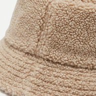 Beige sherpa fleece bucket hat with textured, cozy fabric closeup