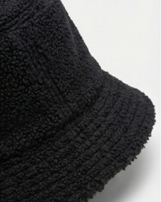 Black sherpa fleece bucket hat with textured fabric on a plain background