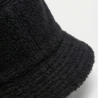 Black sherpa fleece bucket hat with textured fabric on a plain background