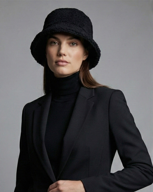 Woman in black blazer, black turtleneck, and black textured bucket hat