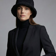 Woman in black blazer, black turtleneck, and black textured bucket hat
