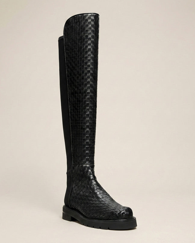 Black knee-high woven leather boot with textured pattern on a neutral background