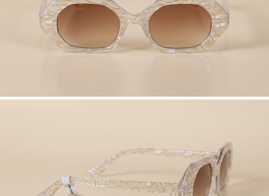 Geometric sunglasses with clear gold-patterned frames and brown gradient lenses on beige background