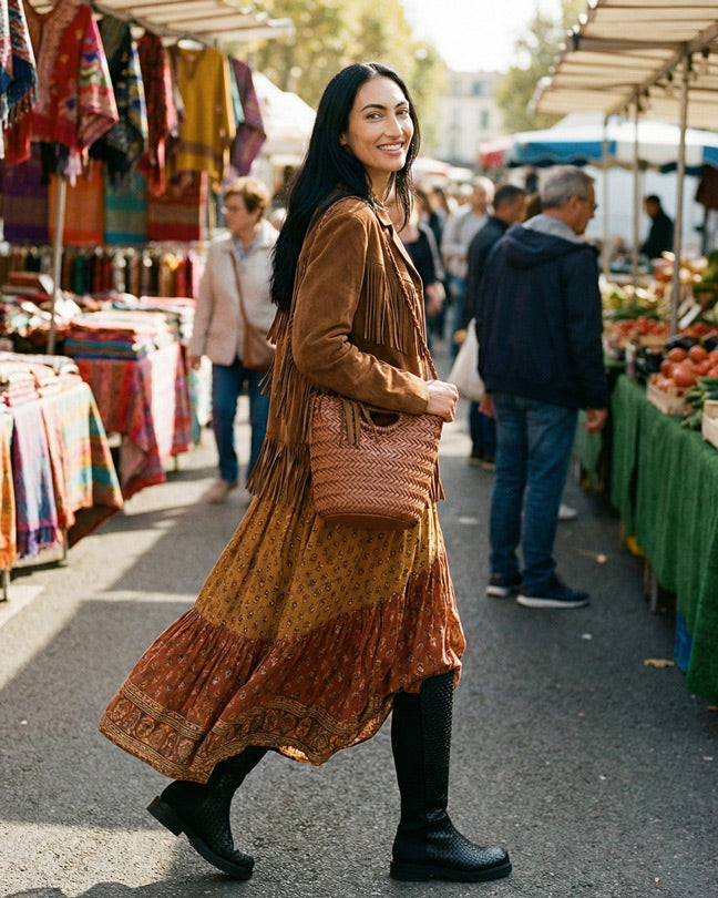 Woman in boho dress and fringe jacket with woven bag shopping at outdoor market