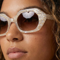 Woman wearing oversized geometric sunglasses with marbled white and gold frames