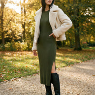 Woman in olive ribbed midi dress, shearling jacket, and black boots outdoors in autumn